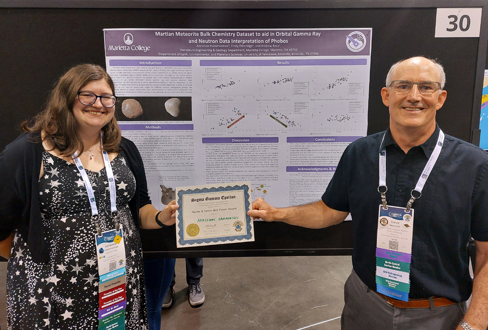 National President hands certificate to a presenter.  They are standing in front of a research Poster